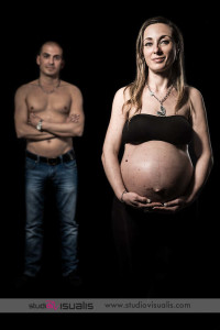 Donna incinta al nono mese con marito in background Ritratto in studio di una donna incinta davanti e marito in secondo piano