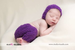 Neonata addormentata con cappellino e pantaloncini di lana viola