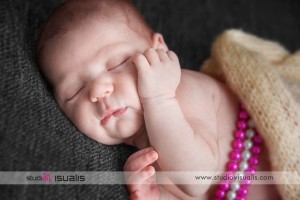 Neonata che dorme con mano sul viso e collana di perle