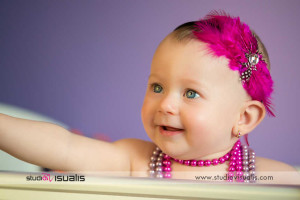 Bambina sorridente con cerchietto con piume fucsia