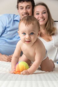 primo piano bambino gioca su lettone e genitori su sfondo