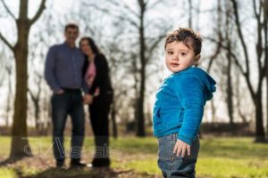 Bambino nel bosco con genitori sullo sfondo