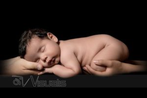 neonato addormentato su mani di genitori